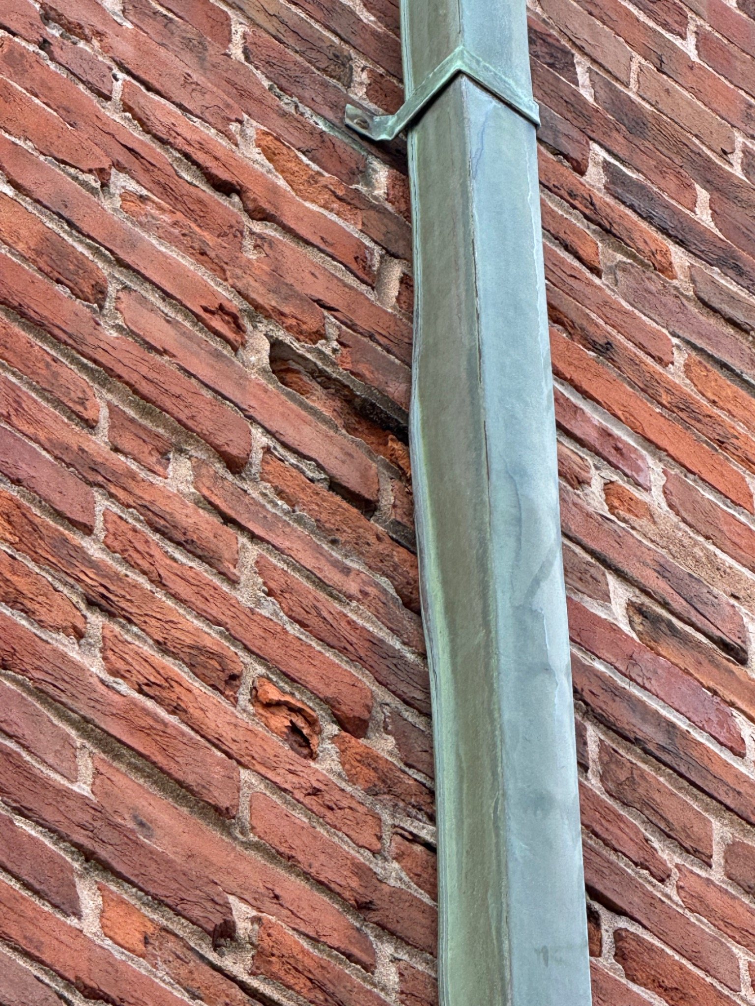 Historic brick masonry with face deterioration near a downspout