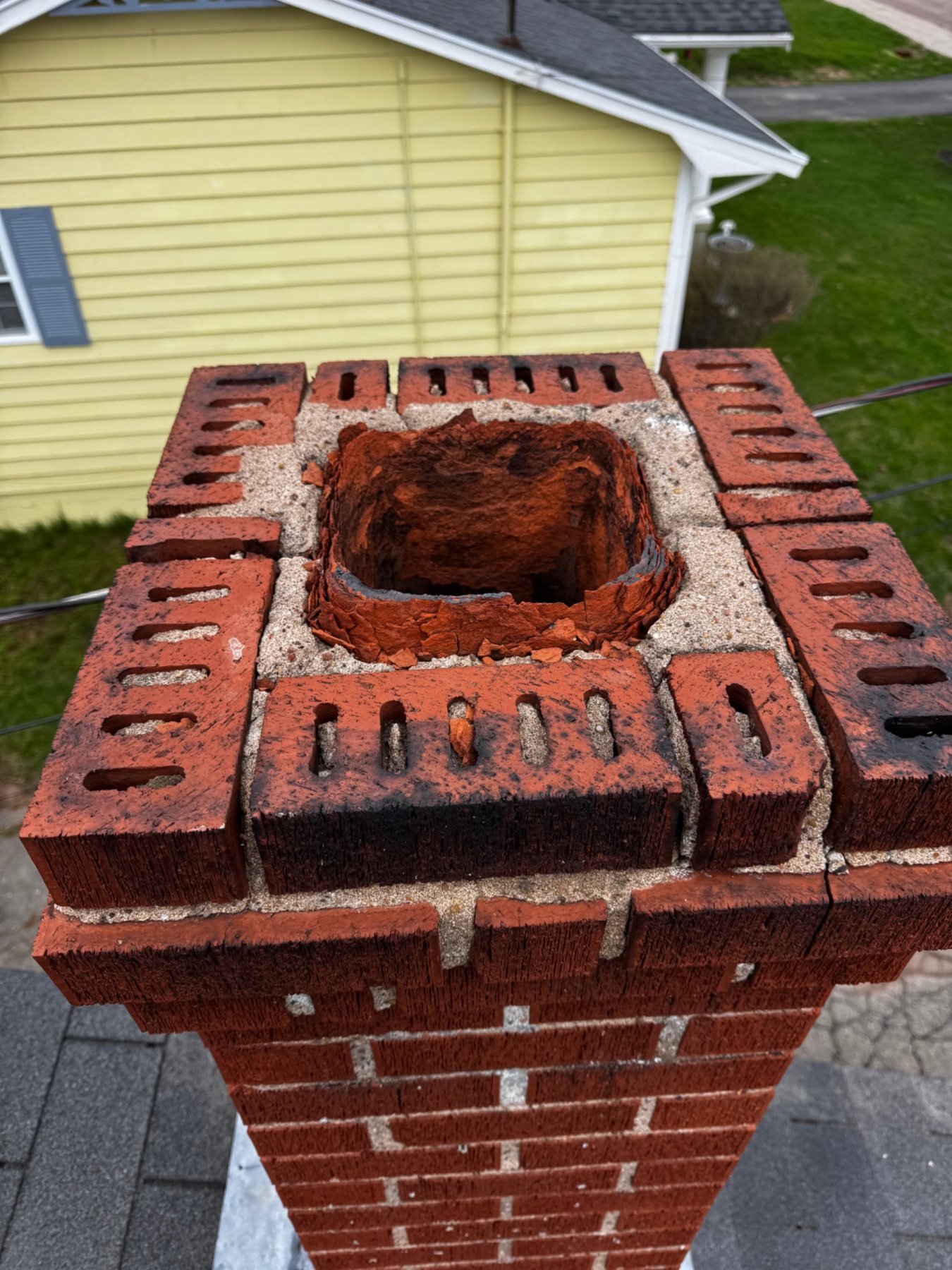 Masonry chimney top with visible deterioration around the flue liner