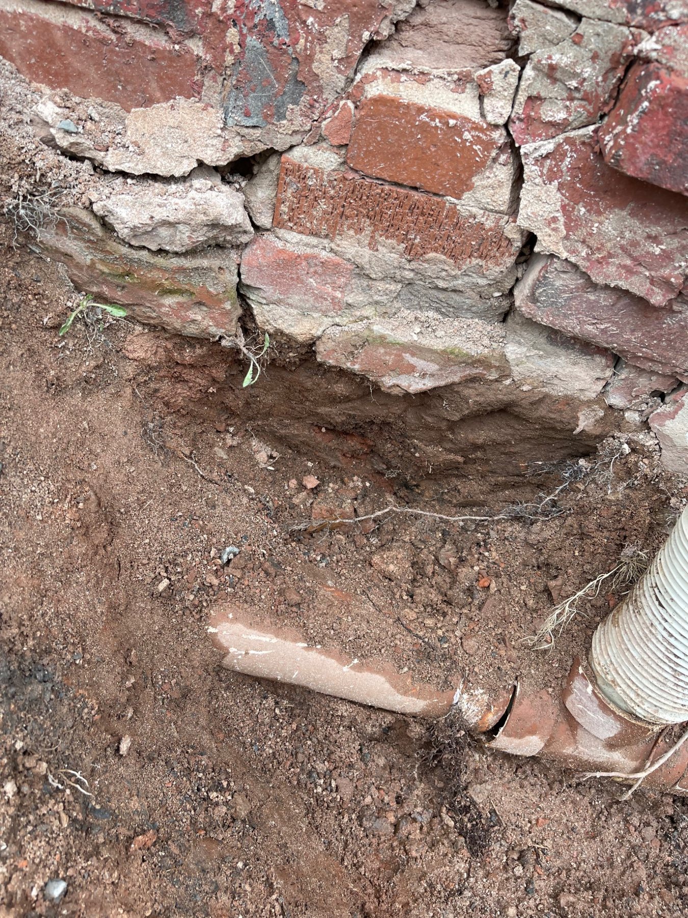 Exposed base of an older stone foundation showing masonry conditions near grade